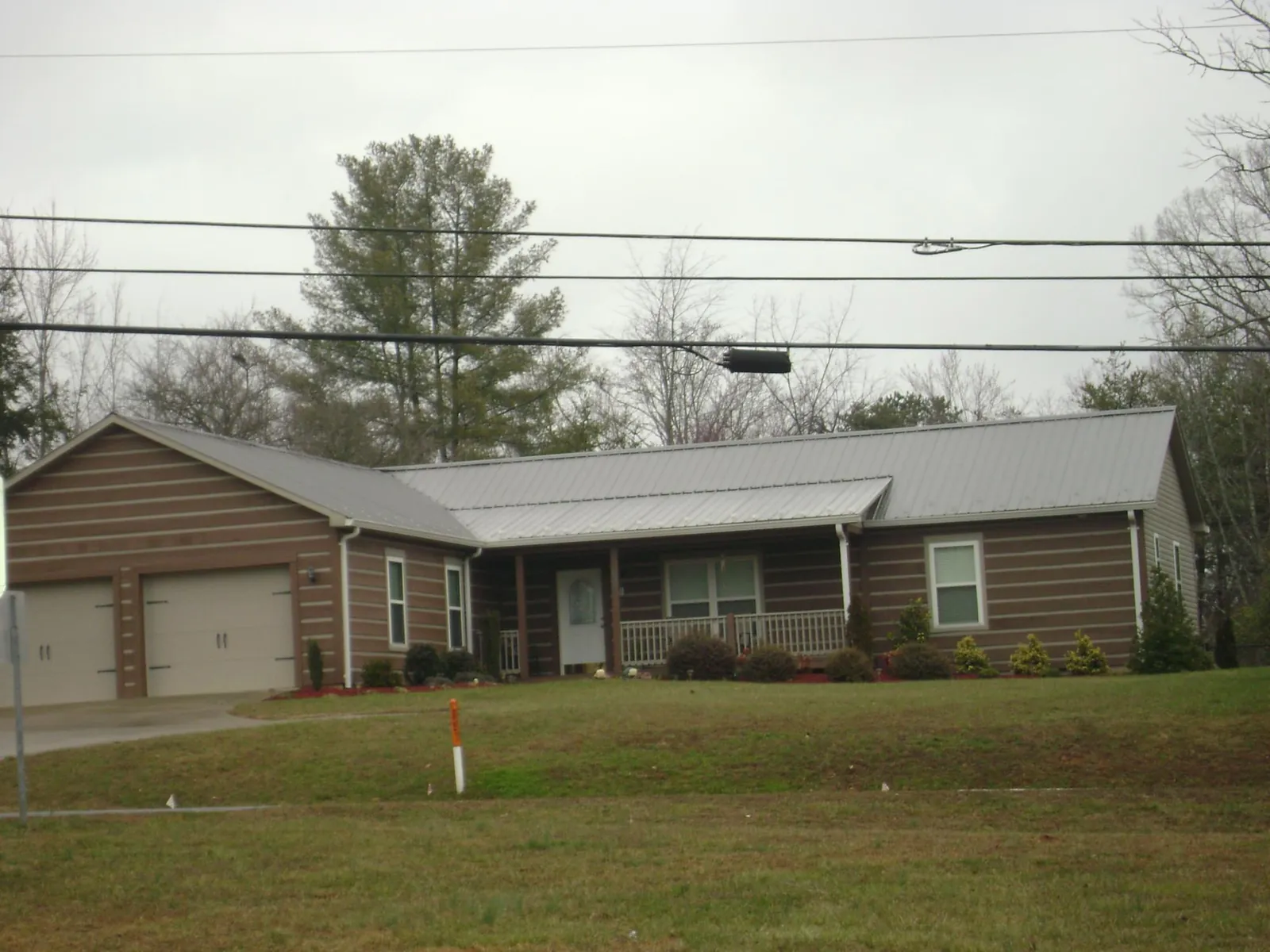 Gray metal roof on a log sided ranch home with a front porch in Crescent